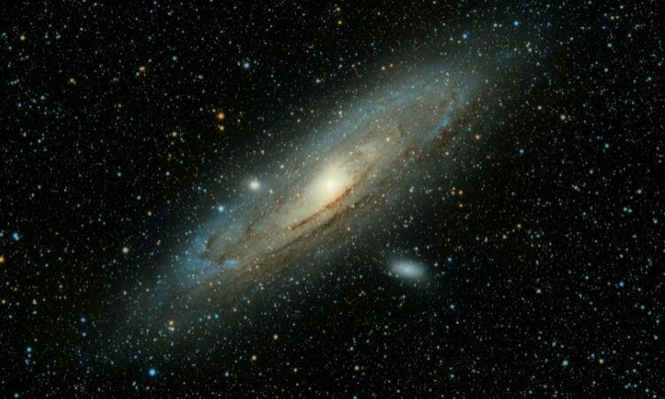 A spiral galaxy surrounded by numerous stars in deep space, with a bright central core and distinct spiral arms visible.