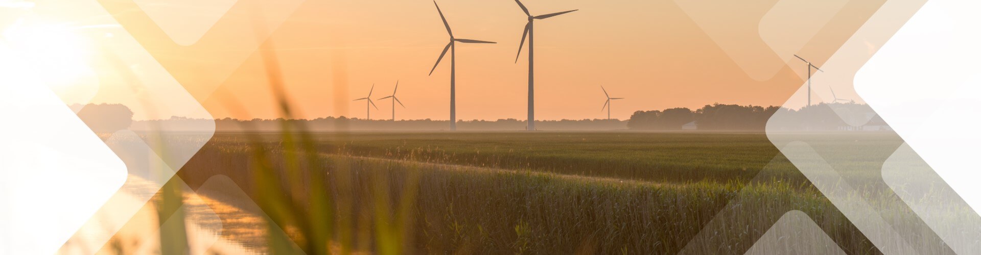 Wind turbines in a field at sunset, with grass in the foreground and a hazy sky. Geometric shapes overlay the image.