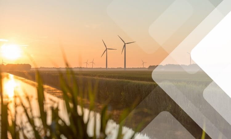 Wind turbines in a grassy field at sunset with a reflective waterway in the foreground. Geometric pattern overlays the scene.