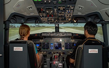 A UniSQ student and staff member using a UniSQ flight simulator.