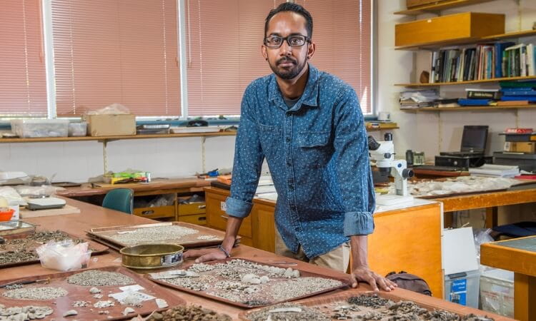 a man standing over archeological artefacts