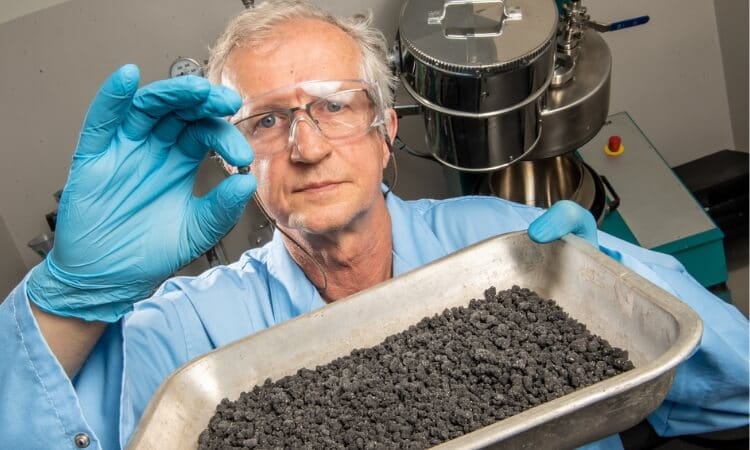 a man with material produced by a granulator 