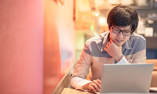 A focused individual working on a laptop in a well-lit room.