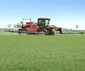 Agricultural sprayer machine operating in a green field.