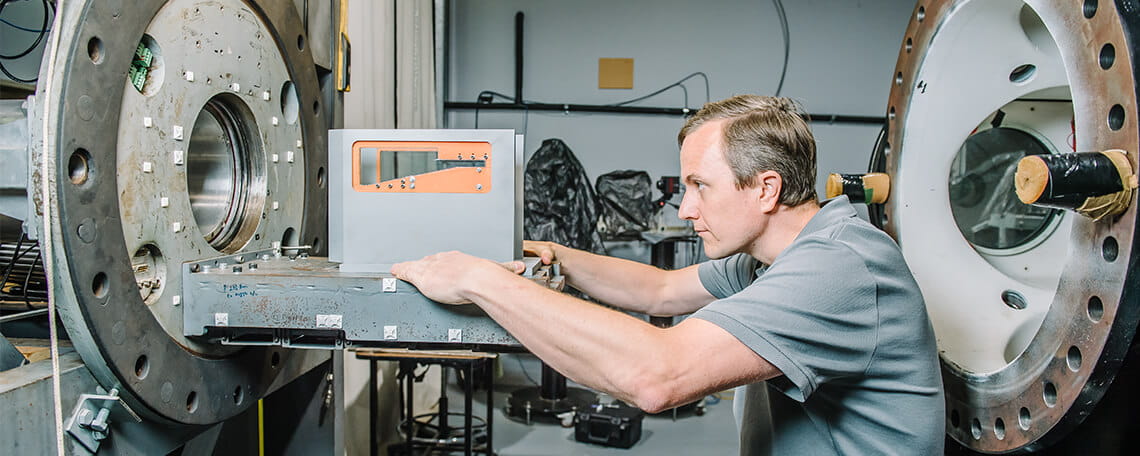 Technician calibrating or inspecting equipment in an industrial setting.