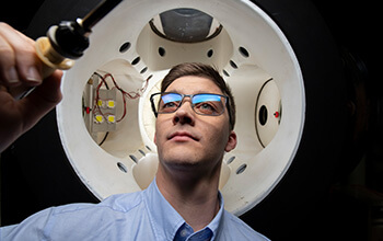 Man inspecting equipment with a flashlight inside a large mechanical device.