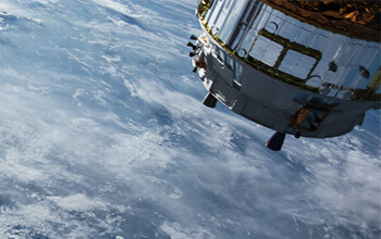 A satellite orbits earth against a backdrop of swirling clouds.