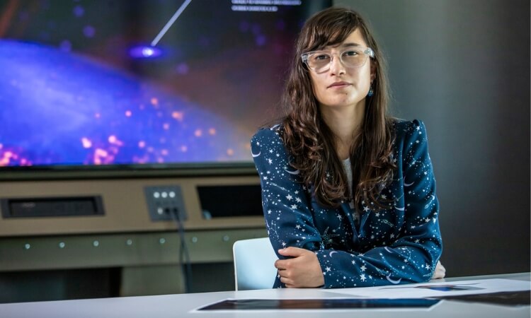woman sitting at desk with visual of space behind her