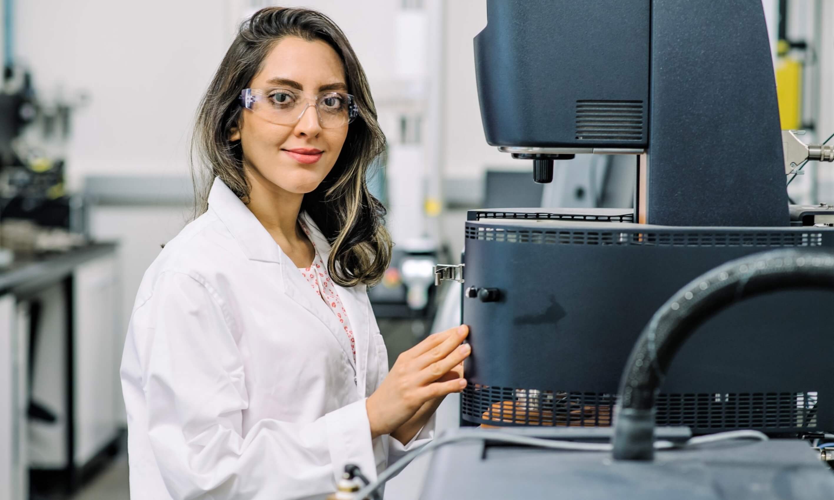 woman standing beside a machine smiling