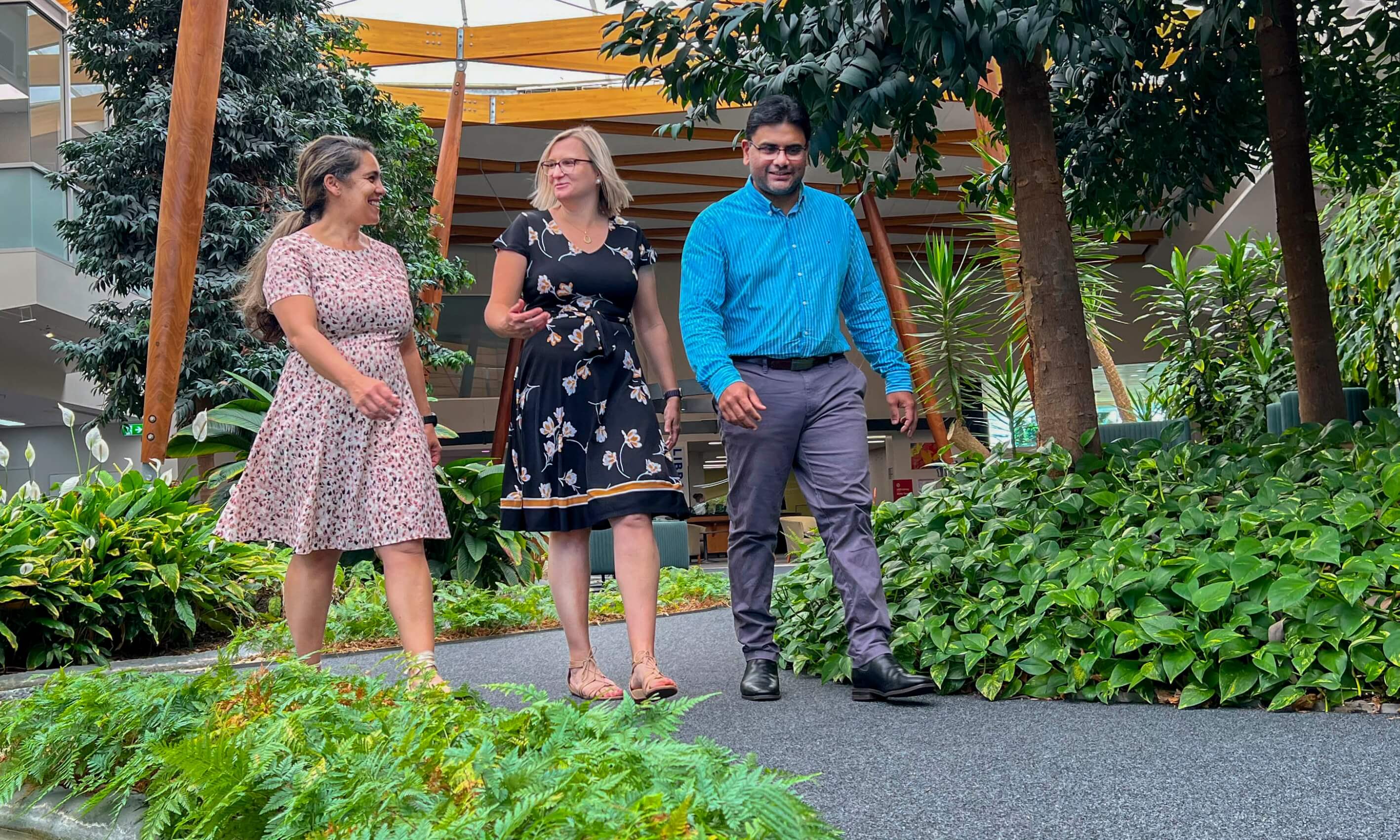 three staff members smiling as they walk through the library