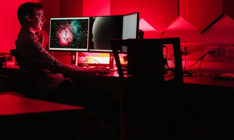 man sitting at desk studying space