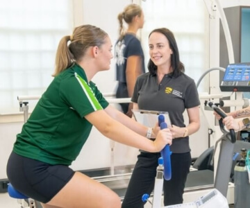 Personal trainer assisting a client with her workout in a gym.
