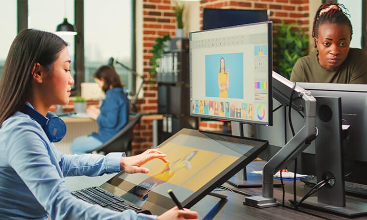 A lady working on a design document on a computer. 