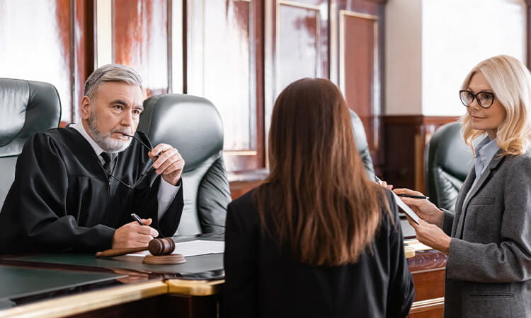 Two lawyers talking to a judge in court at the bench.