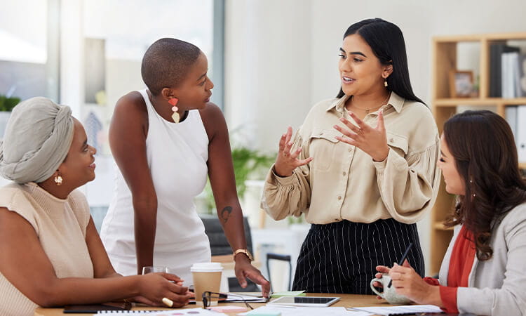 Four women talking in a professional setting.