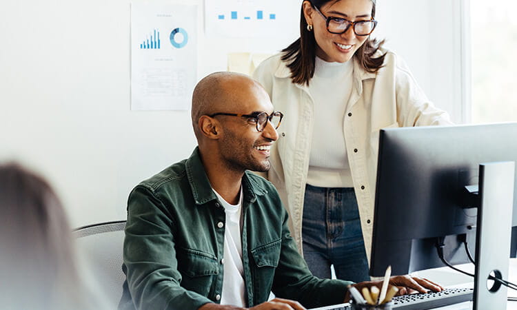 Two people looking at a computer. 