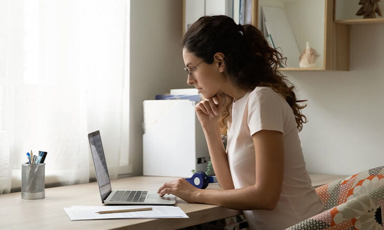 Lady working on a laptop in a home office.