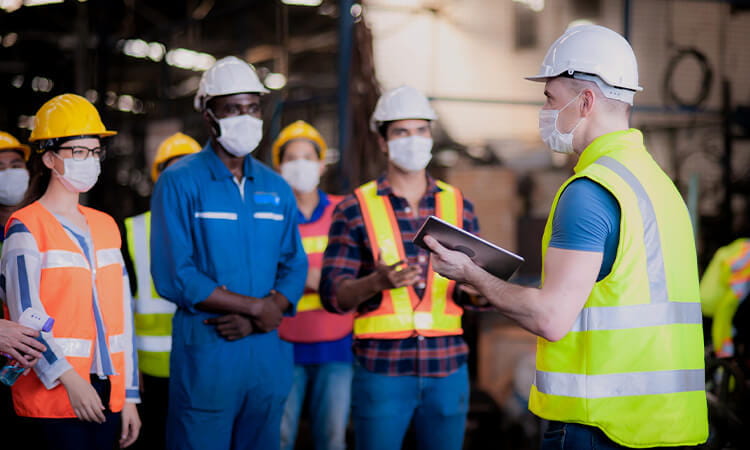 One man in high vis, holding an iPad address a group of people.