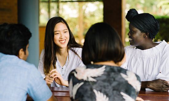 Four people engaged in a friendly conversation around a table.