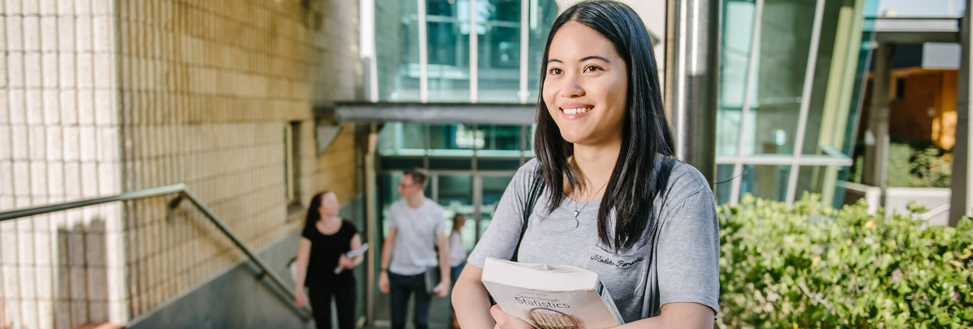 Female student carrying books coming out of campus building