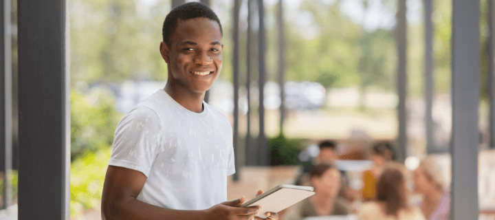 UniSQ student holding a notepad smiling at the camera