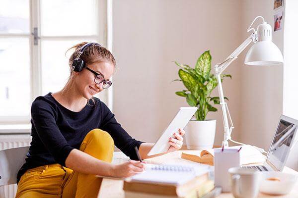 Student sitting at desk with headphones on.