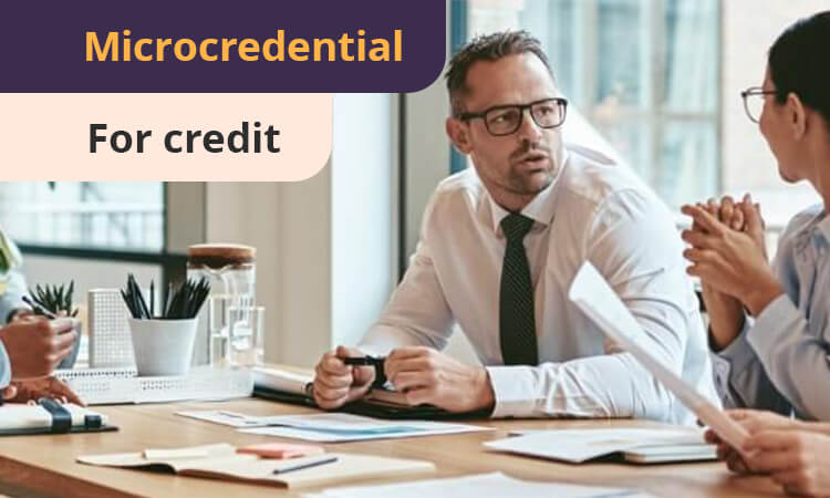 A group of professionals in a meeting room discussing documents, with a banner reading "Microcredential For credit" in the top left corner.