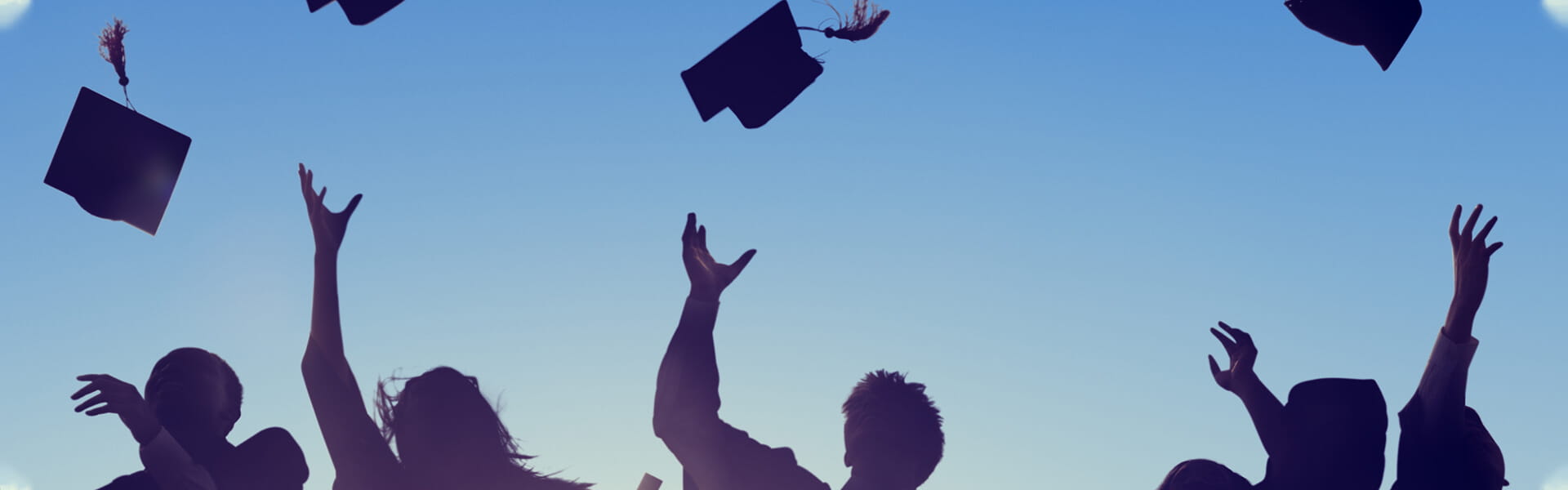 Graduates throwing their mortarboards into the sky.