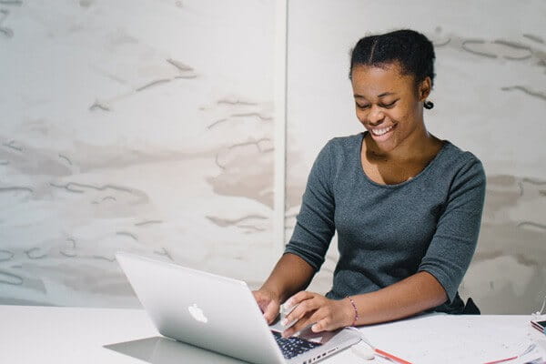 Image of a female, seated at a desk working at a computer.