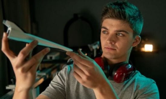 A young man examining a 3d printed object in a workshop.