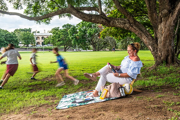 Mother reading with children playing in the background.