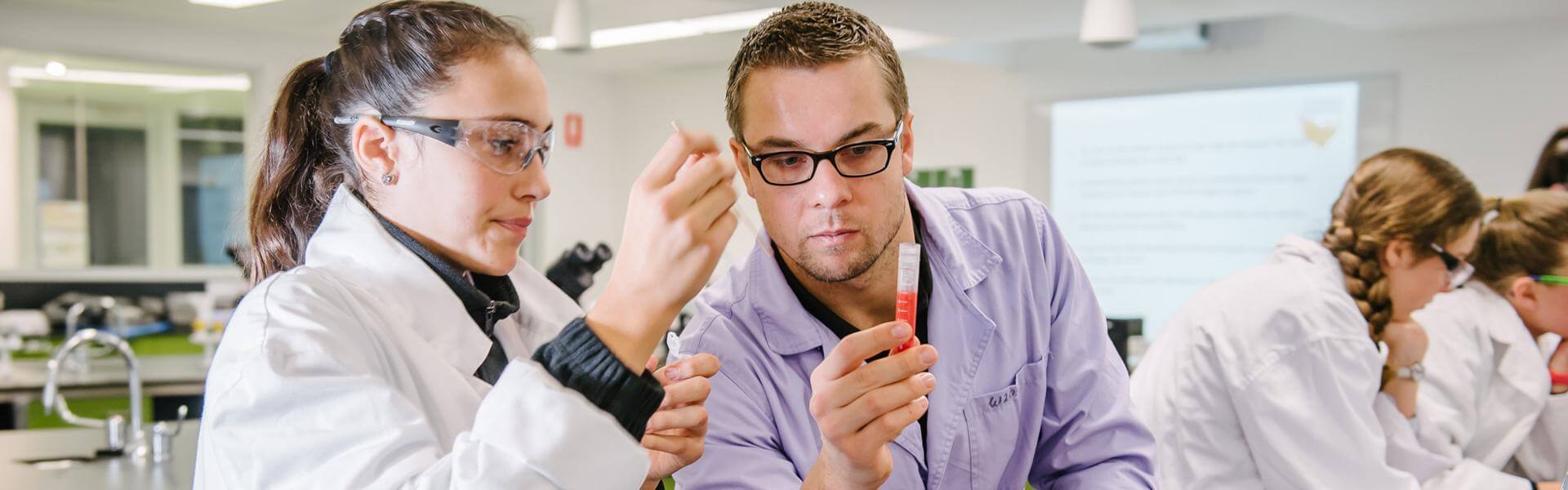 A teacher and student in a science lab inspecting a test  tube.