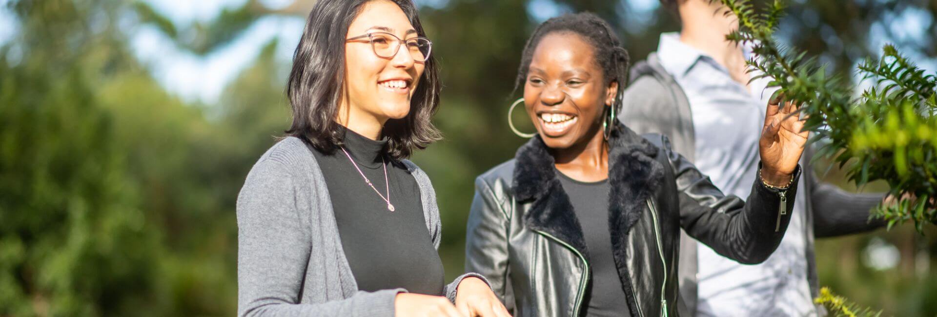 Two women smiling and walking outdoors on a sunny day.