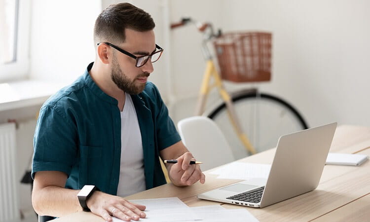 Student sitting at desk working on laptop. 