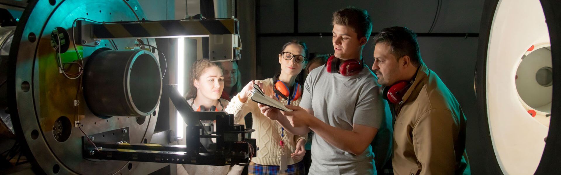 students looking at rocket equipment at university