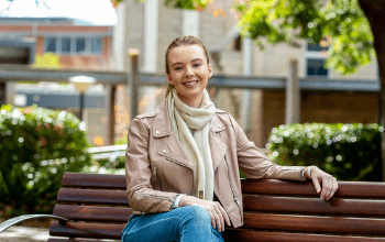 USQ student Georgia sitting on a bench at Toowoomba campus