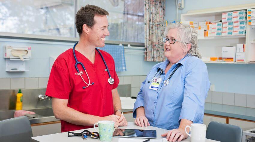 Two healthcare professionals having a conversation in a hospital staff room.