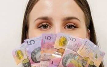 Woman covering her mouth with various denominations of banknotes.