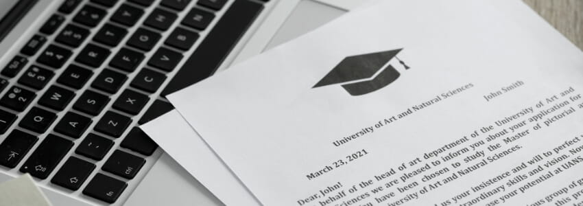 A laptop with a university offer letter on top of the keyboard.