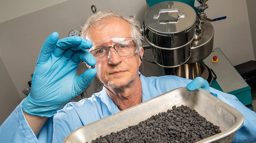 Man holding pan with granulated material