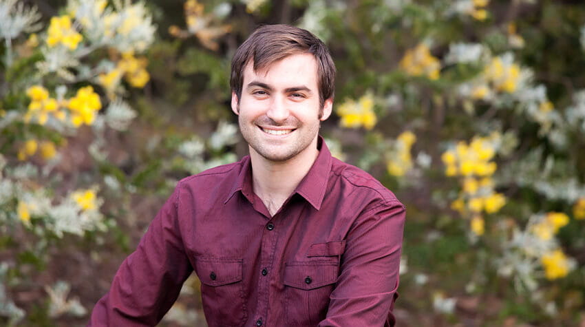 Man sitting in flowers and smiling. 
