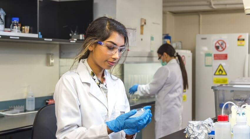 Scientist examining a sample in a laboratory setting.