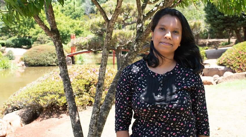 Buddhika is standing in the Japanese Garden, UniSQ Toowoomba, smiling at the camera.