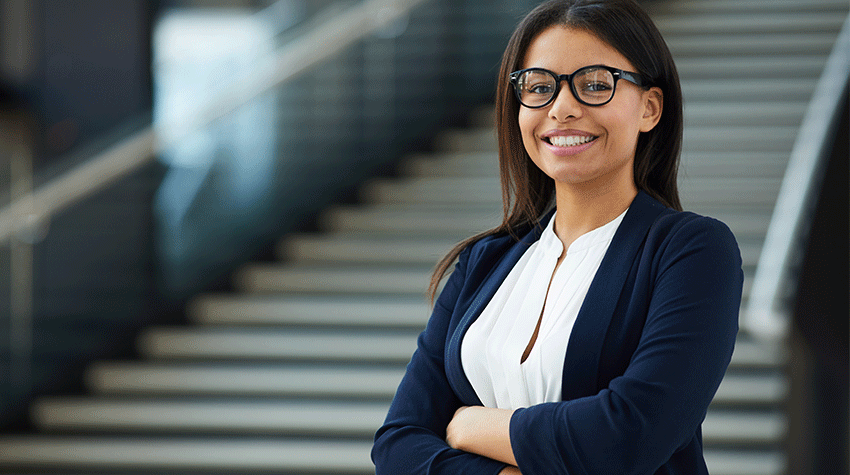 Business woman looking at camera in front of staircase.