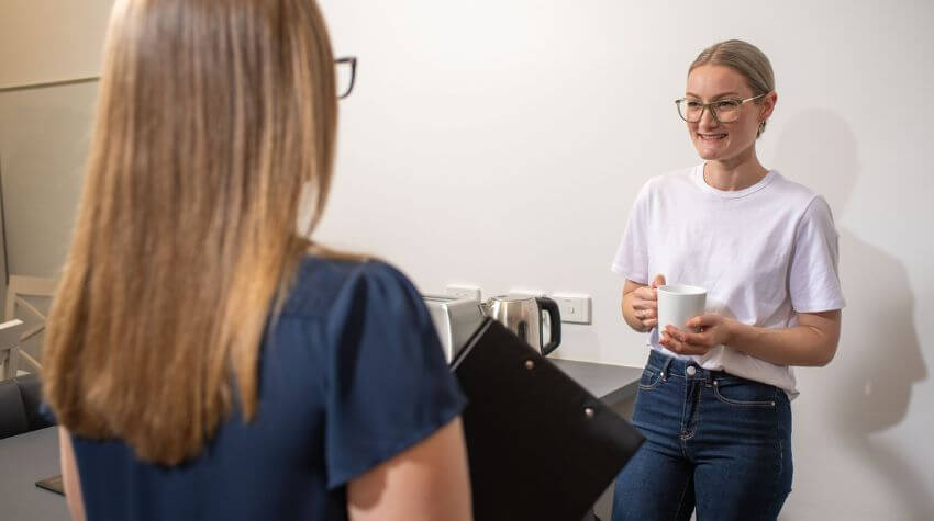 Photo of Casey talking to a friend in the kitchen.