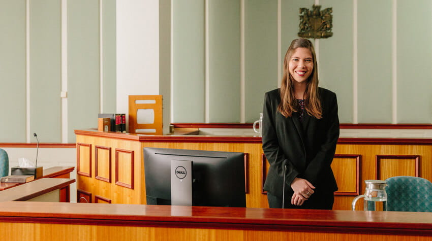 Erin is standing in a courtroom, smiling at the camera.