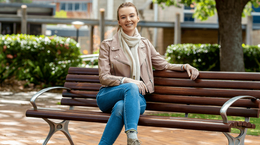 UniSQ student Georgia Poole sitting on a chair on campus