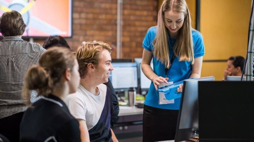 A teacher assists students during a computer class.