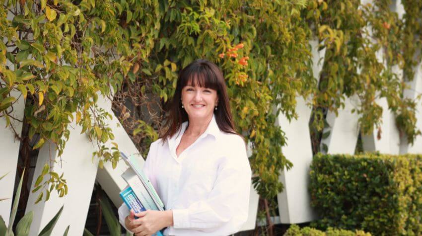 Melanie standing with a stack of books.