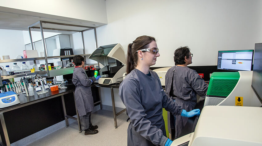 Three people at lab, surrounded by equipment